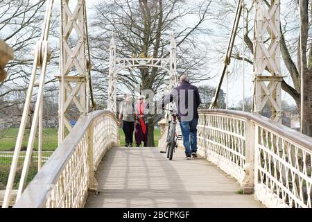 Hereford, Herefordshire Royaume-Uni - Dimanche 5 avril 2020 - les gens s'exercent au soleil de printemps en traversant le pont piéton étroit Victoria ( pour commémorer le Jubilé de diamant de la Reine Victoria en 1897. ) Au-dessus de la rivière Wye à Hereford pendant la crise du coronavirus. Photo Steven May / Alay Live News Banque D'Images