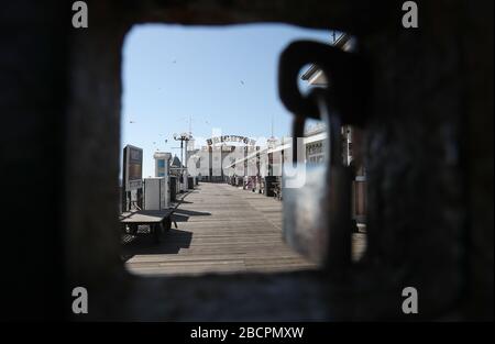 Vue générale du Brighton Palace Pier à travers une porte fermée à cadenas, tandis que le Royaume-Uni continue à se bloquer pour aider à freiner la propagation du coronavirus. Banque D'Images