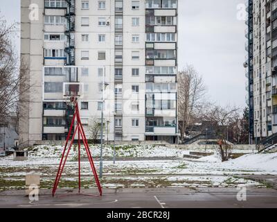 Le terrain de basket-ball en déroute devant les bâtiments communistes du quartier de Novi Beograd, ou de New Belgrade, en Serbie, en hiver, est couvert de neige. Banque D'Images