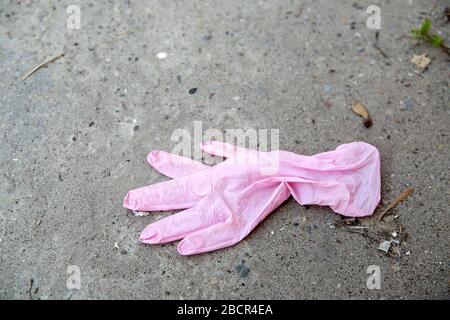 Gants médicaux roses jetés dans la rue, sur le sol. Banque D'Images