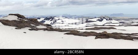 Vue panoramique sur trois randonneurs traversant un champ de neige lors de la randonnée à Fimmvörðuháls, en Islande Banque D'Images