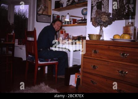 Un père assis à son bureau souriant, travaillant à la maison dans les années 1970. 1973 ROYAUME-UNI Banque D'Images