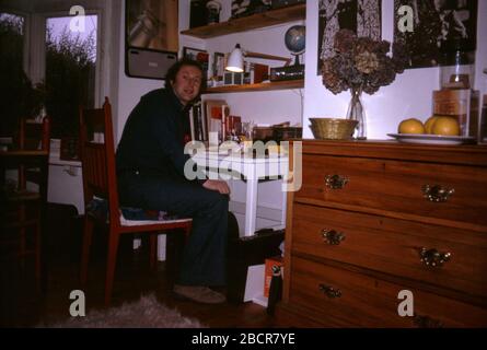 Un père assis à son bureau souriant, travaillant à la maison dans les années 1970. 1973 ROYAUME-UNI Banque D'Images