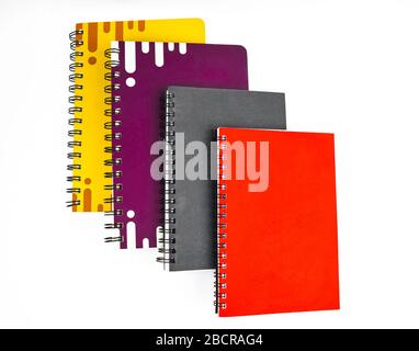 Journal de quatre notes en papier de couleur rouge noir violet et jaune placé l'un sur l'autre avant un fond blanc Banque D'Images
