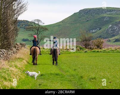 East Lothian, Écosse, Royaume-Uni. 5 avril 2020. Météo au Royaume-Uni : l'est du pays ressent enfin la chaleur du soleil de printemps car ceux qui vivent dans la zone rurale prennent leur exercice quotidien. Une femme et une fille qui monte sur les chevaux autour des bords des champs de récolte Banque D'Images