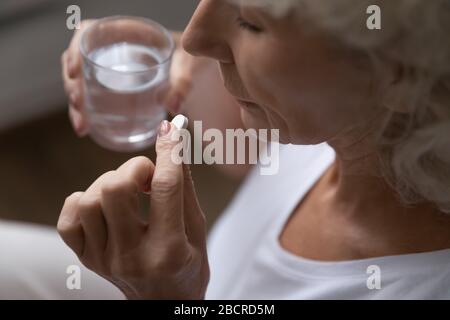 Femme à la retraite tenant la pilule et le verre d'eau. Banque D'Images