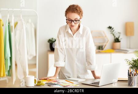 Styliste sérieux de la mode travaillant et debout au bureau Banque D'Images