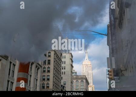 La vapeur monte et dévie parmi les bâtiments Midtown Manhattan Fifth Avenue devant l'Empire State Building à New York City NY USA le décembre 2018. Banque D'Images