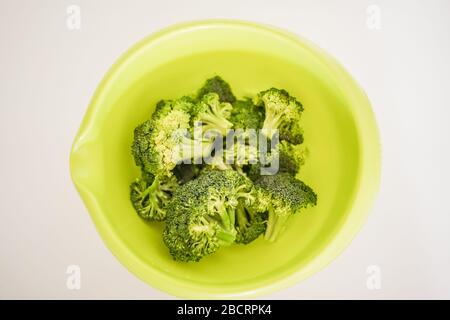 Gros angle haut en bas de bol vert vif et lumineux rempli de tiges de brocoli mûres prêtes pour une préparation de repas délicieuse et saine Banque D'Images