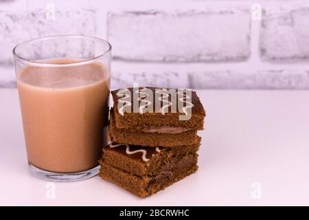 Lait au chocolat dans un verre et gâteau au chocolat sur fond blanc. Espace de copie. Banque D'Images