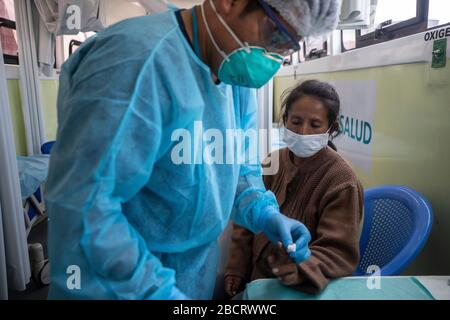 02 avril 2020, Pérou, Lima: Une infirmière dans un costume de protection traite une femme sans abri qui a été placée dans un abri d'urgence contre la propagation du coronavirus. Les personnes sans domicile pourront rester dans la arène pendant le couvre-feu imposé par le gouvernement. Les Péruviens ne sont autorisés à quitter la maison que pour acheter de la nourriture ou des médicaments. Au 03.04.2020, 1414 personnes dans le pays sud-américain avaient été infectées par le nouveau coronavirus, 55 patients étaient morts. Photo: Cesar Campos/dpa Banque D'Images