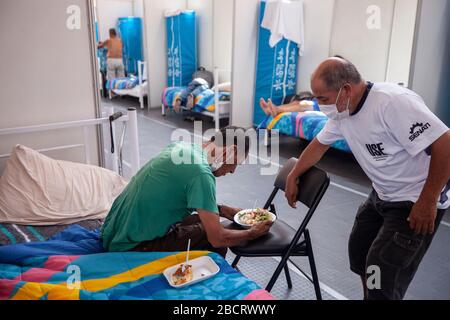 02 avril 2020, Pérou, Lima: Un homme portant un masque de visage est un homme sans abri alors qu'il mange dans un abri d'urgence qui a été construit dans un anneau de taureaux à cause du coronavirus. Les gens sans maison pourront rester dans la arène pendant le couvre-feu du gouvernement. Les Péruviens ne sont autorisés à quitter la maison que pour acheter de la nourriture ou des médicaments. Au 03.04.2020, 1414 personnes dans le pays sud-américain avaient été infectées par le nouveau coronavirus, 55 patients étaient morts. Photo: Cesar Campos/dpa Banque D'Images