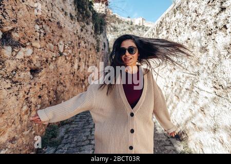 La jeune femme marche avec bonheur entre les murs historiques sur une allée étroite. Concept de tourisme et de voyage Banque D'Images