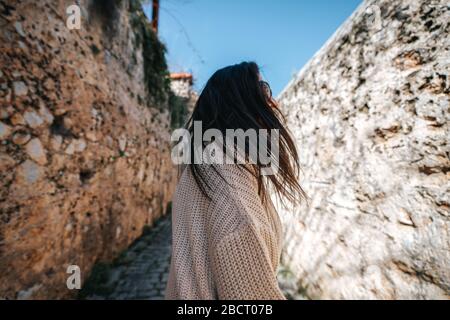 La jeune femme marche avec bonheur entre les murs historiques sur une allée étroite. Concept de tourisme et de voyage Banque D'Images