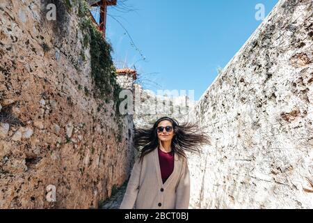 La jeune femme marche avec bonheur entre les murs historiques sur une allée étroite. Concept de tourisme et de voyage Banque D'Images