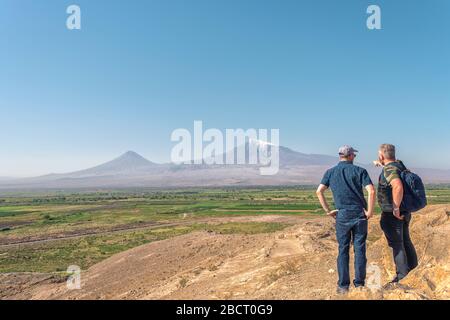 Panorama de montagne Ararat en Arménie avec deux hommes debout au sommet d'une montagne et regardant une vallée Banque D'Images