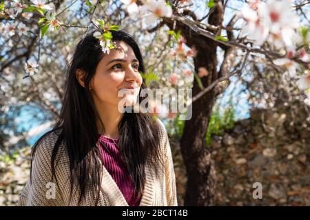 Jeune femme profitant de la vue et de la lumière du soleil sur son visage sous l'arbre de Plum avec des fleurs Banque D'Images