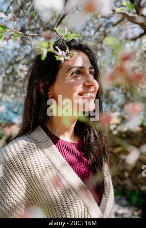 Jeune femme profitant de la vue et de la lumière du soleil sur son visage sous l'arbre de Plum avec des fleurs Banque D'Images