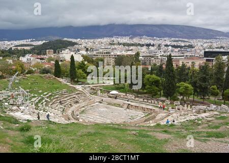 Athènes, Grèce - 24 octobre 2015 : ruines grecques anciennes du théâtre Dionysus, ruines au milieu d'une herbe verte luxuriante. Vue depuis le sommet de l'Acropole en journée nuageux. Banque D'Images