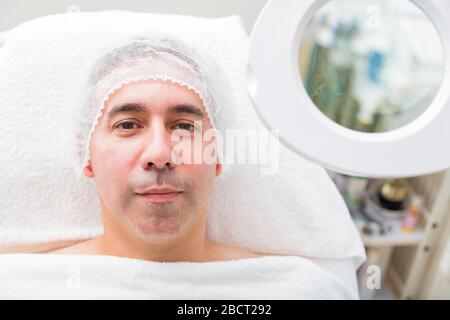 L'homme se trouve près du miroir loupe sur fond blanc Banque D'Images