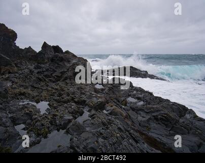 La mer en Islande fouette contre les roches volcaniques lisses Banque D'Images