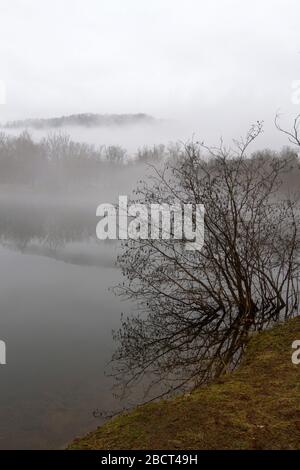 Un brouillard d'hiver fantomatique couvre un lac de montagne dans des tons doux et des silhouettes étoilé Banque D'Images