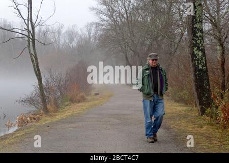 Asheville, Caroline du Nord, 3 janvier 2020: Les gens se séparent de loin sur un chemin solitaire à travers une forêt hazy où il est difficile de voir où ils sont goi Banque D'Images