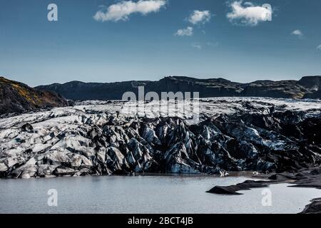 Vue aérienne rapprochée du glacier de Solheimajokull et du lagon glaciaire en face de celui-ci tourné en été avec un drone. Banque D'Images