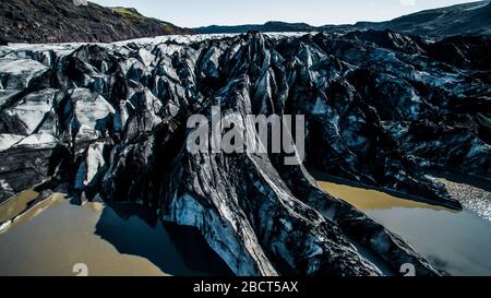 Vue aérienne rapprochée du glacier de Solheimajokull et du lagon glaciaire en face de celui-ci tourné en été avec un drone. Banque D'Images