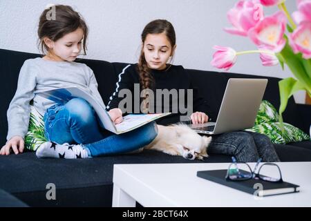 Éducation en ligne, enseignement à distance, homeschooling. Enfants en masque médical étudiant les devoirs pendant la leçon en ligne à la maison dans la tablette numérique de lapto Banque D'Images