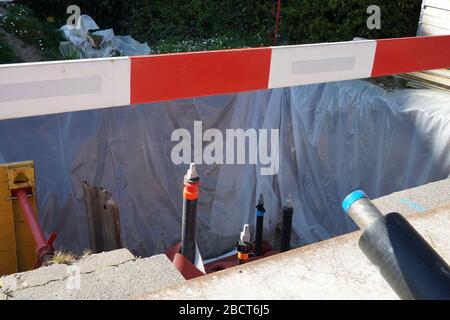 Jonction de tuyaux et de bouts morts de tuyaux dans le puits de construction de génie civil avec une planche de barrière de rouge et blanc au premier plan pour fixer le b Banque D'Images