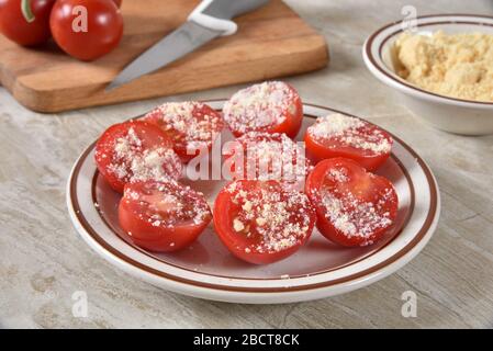 Une plaque de tomates perlées en tranches avec du parmesan saupoudrés sur le dessus Banque D'Images