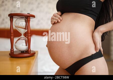Femme enceinte avec ventre pose contre le verre de sable Banque D'Images