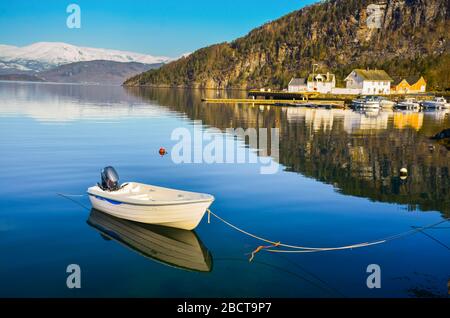 Seul bateau sur un magnifique lac clair en Norvège. Montagnes enneigées en arrière-plan Banque D'Images