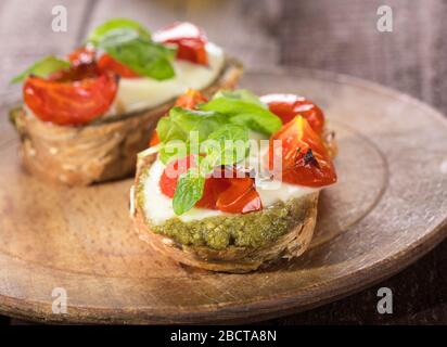 Bruschetta aux tomates, mozzarella, pesto et basilic frais sur fond de bois. Banque D'Images