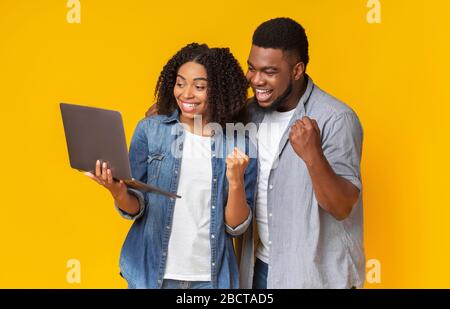 Couple afro-américain souriant regardant les sports sur ordinateur portable ensemble et de la tricherie Banque D'Images