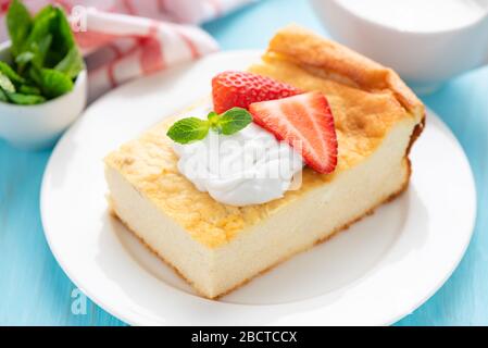 Une délicieuse casserole au fromage cottage avec crème et fraises sur plaque blanche. Gâteau au fromage fait maison parfait pour le petit déjeuner ou en-cas Banque D'Images