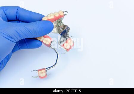 dentisterie orthopédique concept de prothèses avec prothèses amovibles. la main d’un dentiste dans un gant contient un ensemble de prothèses de fermoir sur le haut et le bas Banque D'Images