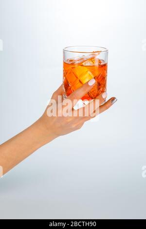 Gros plan d'une main tenant un verre de cocktail negroni sur fond blanc avec espace de copie. Banque D'Images