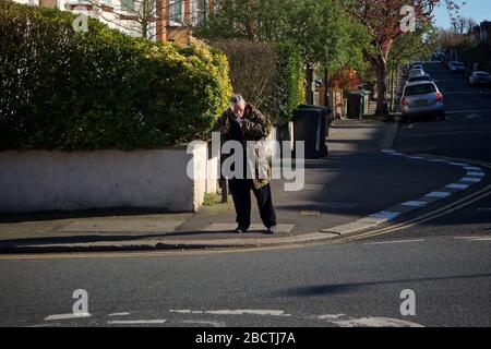 Londres, Royaume-Uni. Coronavirus. Un homme semble fumer ouvertement de crack cocaïne au coin des rues résidentielles, principalement désolées, pendant le covid- 19 Banque D'Images