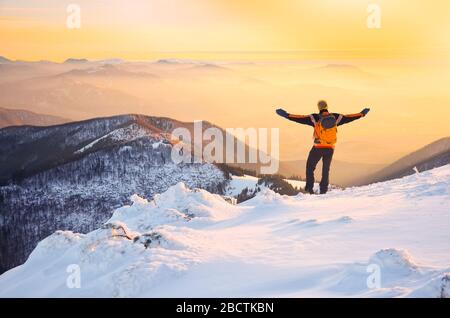 homme aux bras ouverts au-dessus de merveilleux paysage de montagnes dans la brume pendant la soirée d'hiver calme Banque D'Images