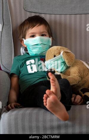 Coronavirus, Covid-19, Boy et son chiot farci dans des masques de protection, quarantaine à la maison Banque D'Images