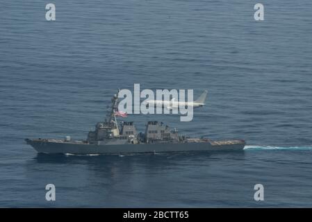 Un avion Poseidon de la marine américaine P-8 survole le destroyer de missile guidé de classe Arleigh Burke USS Donald Cook pendant les opérations du 29 mars 2020 dans l'océan Atlantique. Banque D'Images