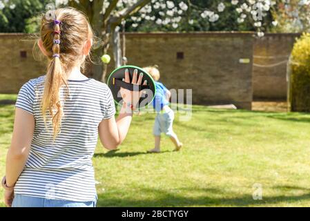 Les enfants qui jouent à l'extérieur d'un frère et d'une sœur jouent à un jeu de balle dans un jardin Banque D'Images