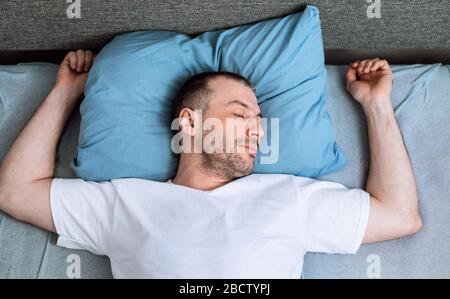 Homme mûr dormant allongé dans le lit dans la chambre, vue du dessus Banque D'Images