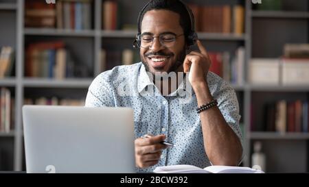 Heureux homme biracial dans le micro-casque étudiant sur un ordinateur portable moderne Banque D'Images