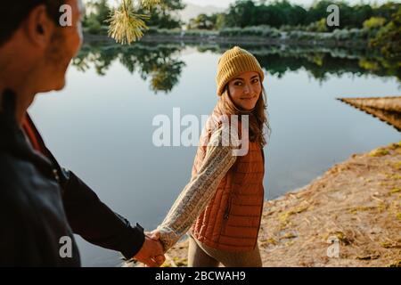 Un couple heureux lors d'une excursion en camping à pied près d'un lac. Homme et femme marchant en tenant les mains près du lac dans la forêt. Banque D'Images