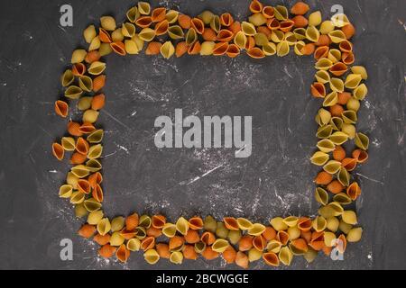 Pâtes Conchiglie Rigate, mélange de coquillages colorés non cuits en forme de rectangle avec un milieu vide. Cuisine italienne texturée concept de fond Banque D'Images