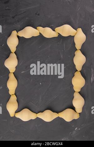 Conchiglie composition de la coquille de pâtes sous la forme d'un rectangle avec un milieu vide sur fond noir avec chemin de découpe. Concept de produits de pâte Banque D'Images