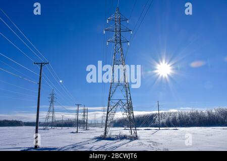 Lignes électriques haute tension aussi loin que l'œil peut voir sur un jour ensoleillé lumineux et ciel bleu clair. Banque D'Images